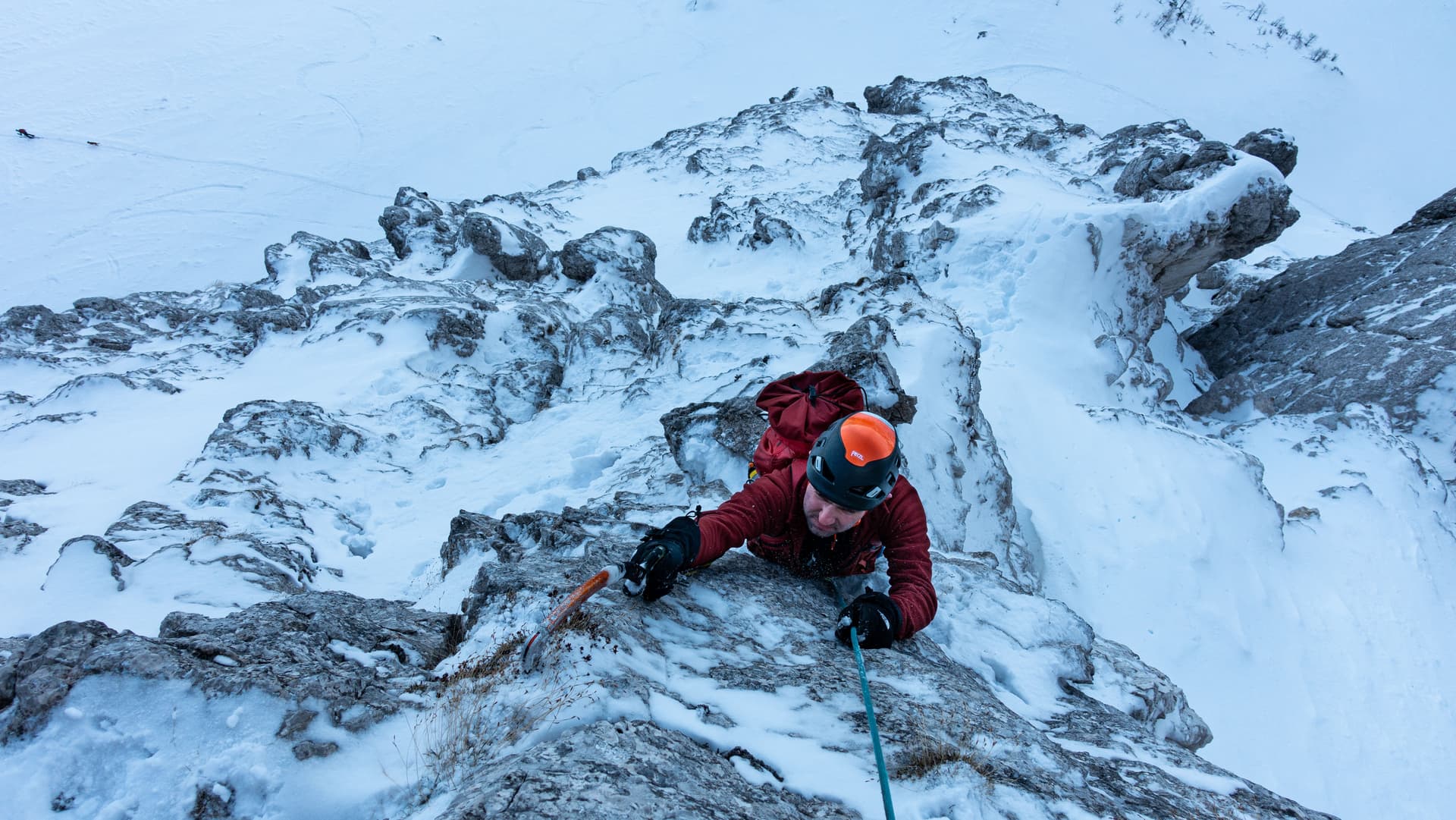Mountaineer ice climbing on snowy, rocky ridge in winter, filename Triglav.
