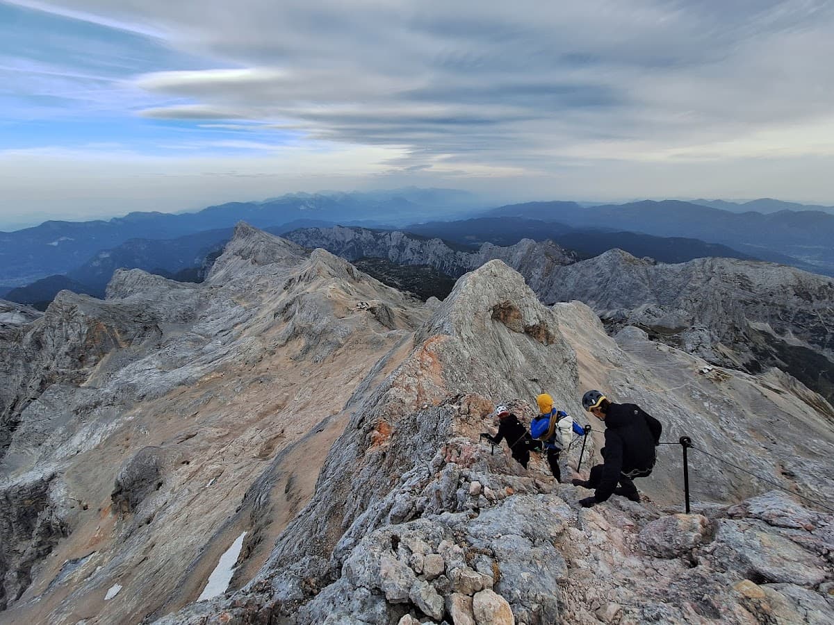 Hikers climbing rocky mountain ridge with exposed peaks and layered blue mountains in background