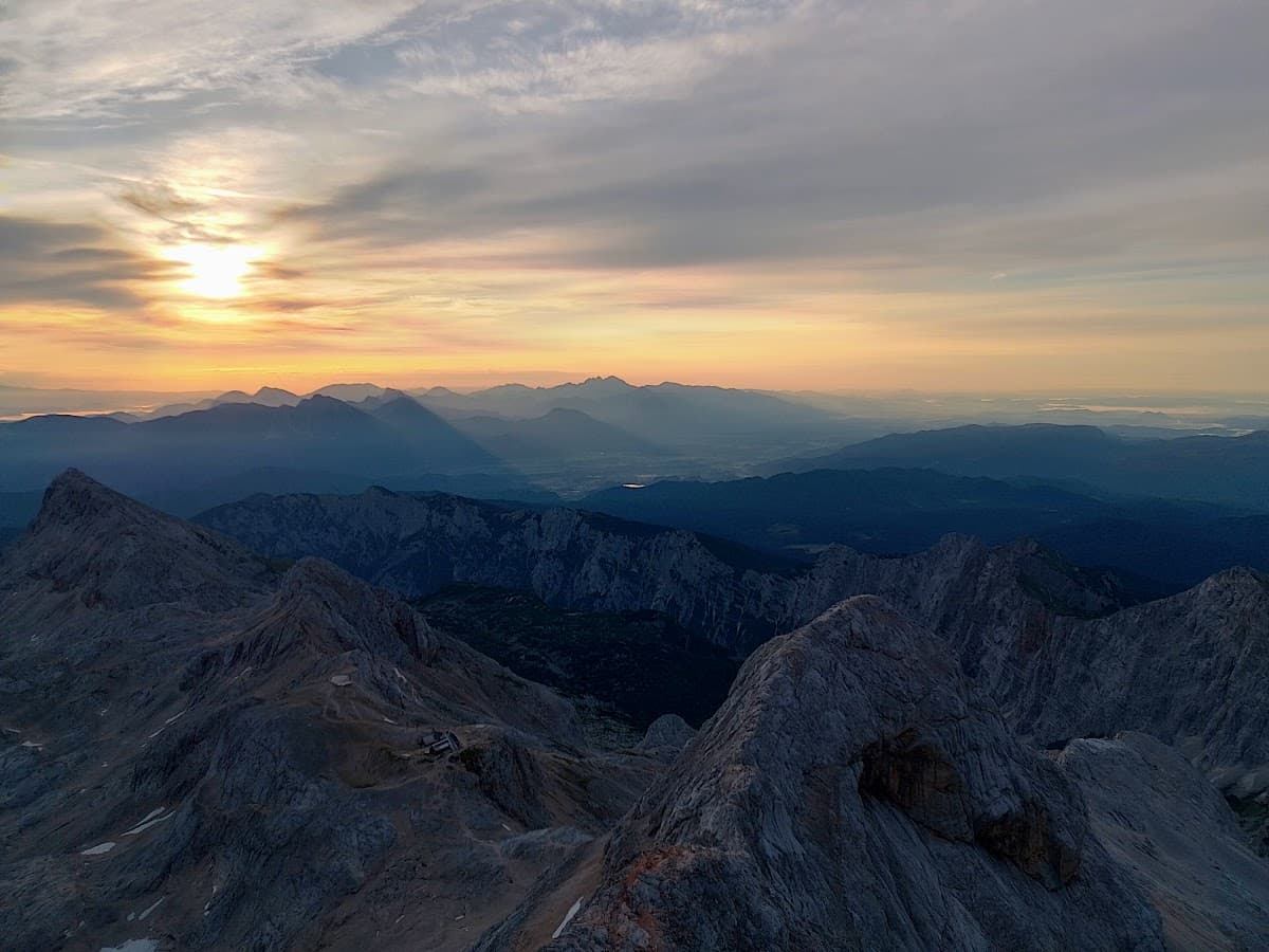 Rugged mountain peaks at sunrise with layers of blue mountain ranges in the distance