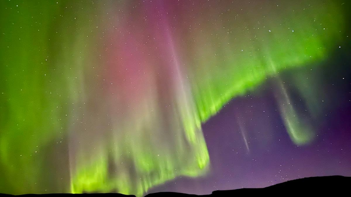 Aurora borealis with green and pink lights in night sky