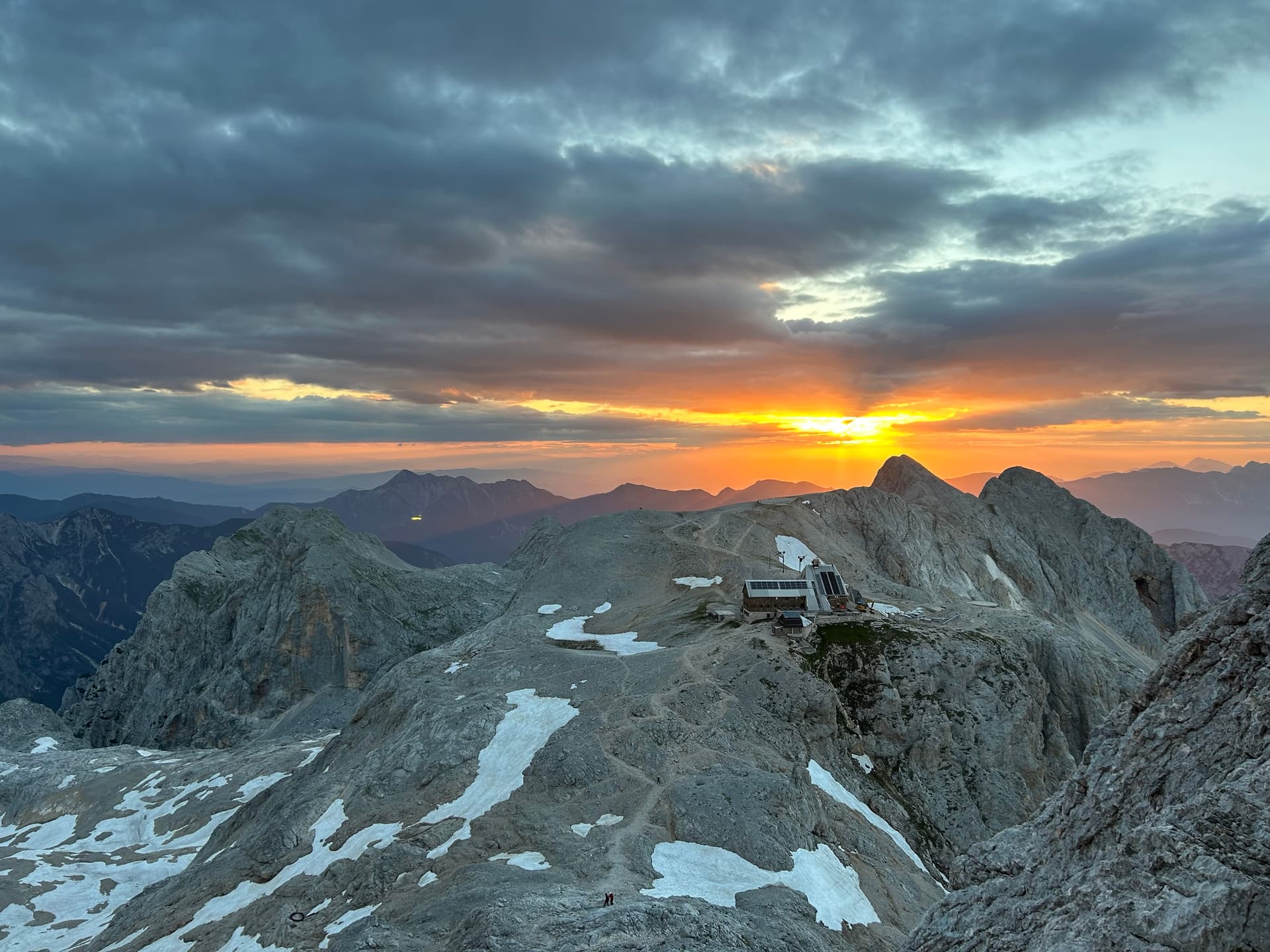 Sunset over the Julian Alps peaks and mountain refuge lodge