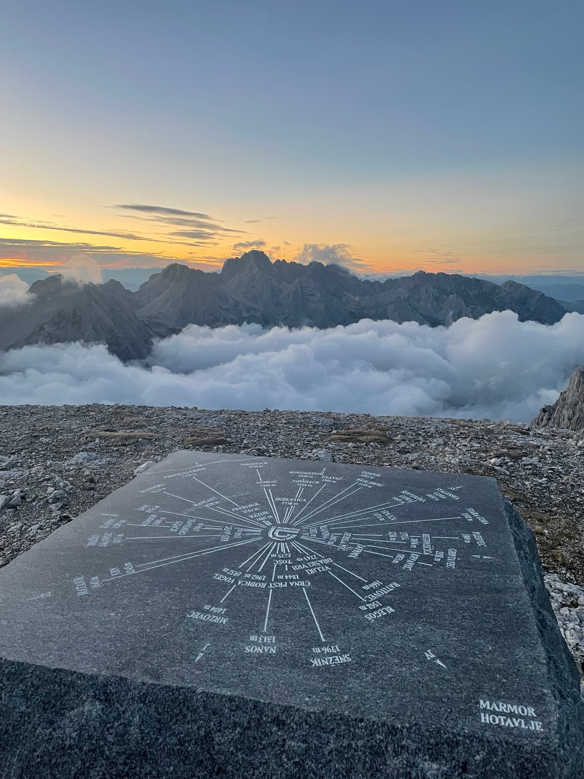 Stone mountain peak orientation plaque overlooking a sea of clouds at sunrise