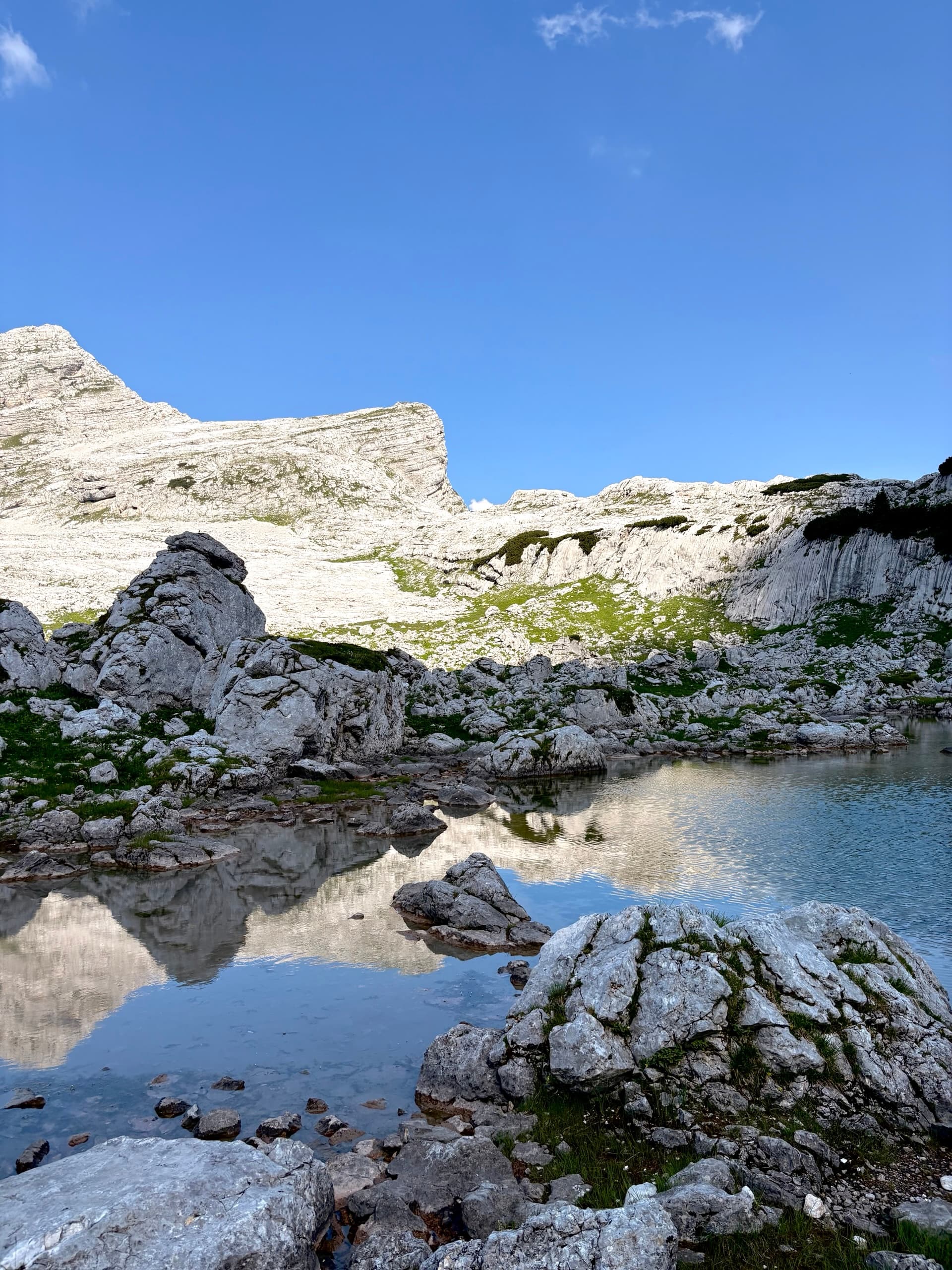Mountain tarn reflecting rocky peaks and clear blue sky