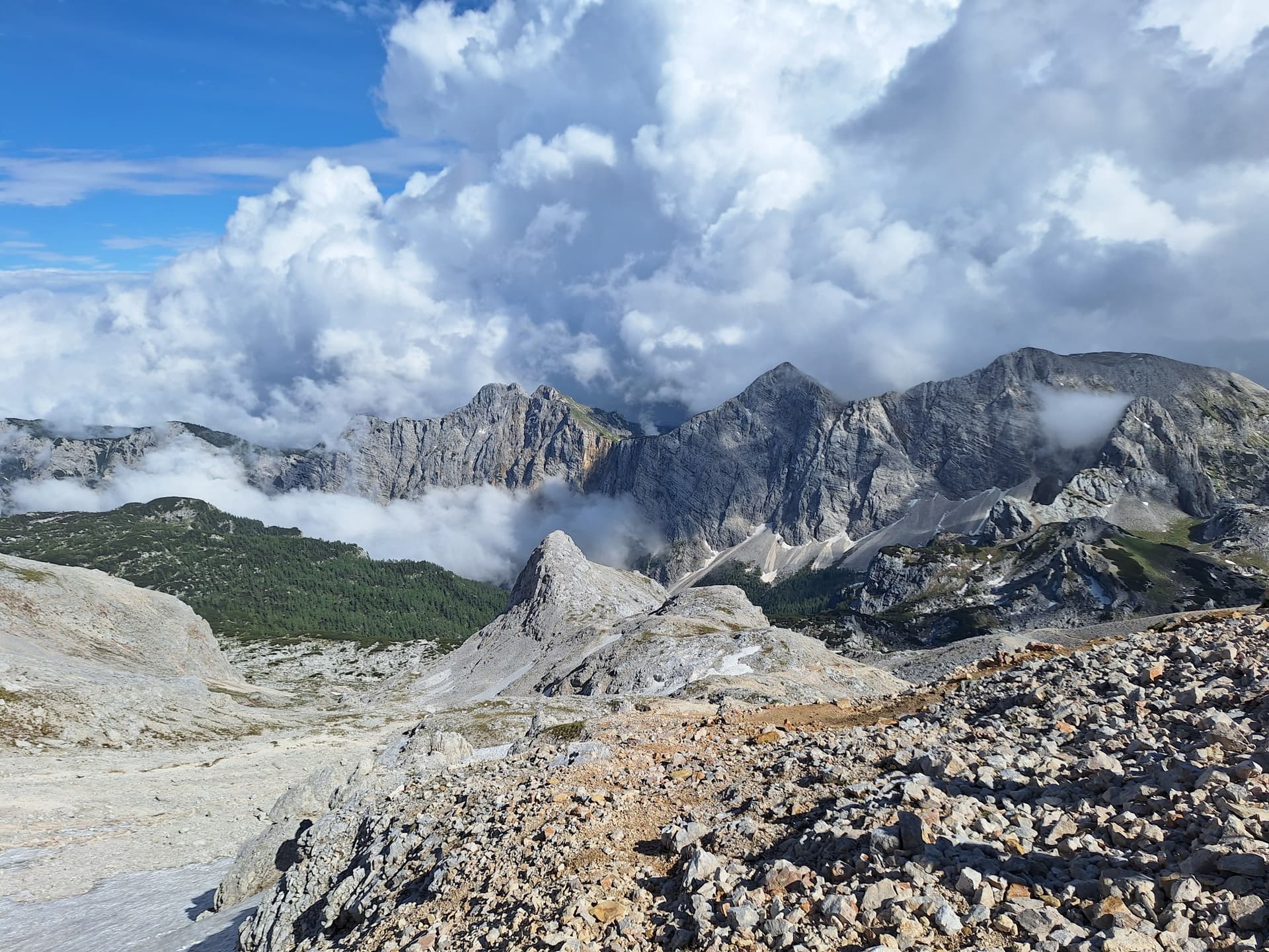 Limestone mountain peaks rising above dense clouds and rocky terrain