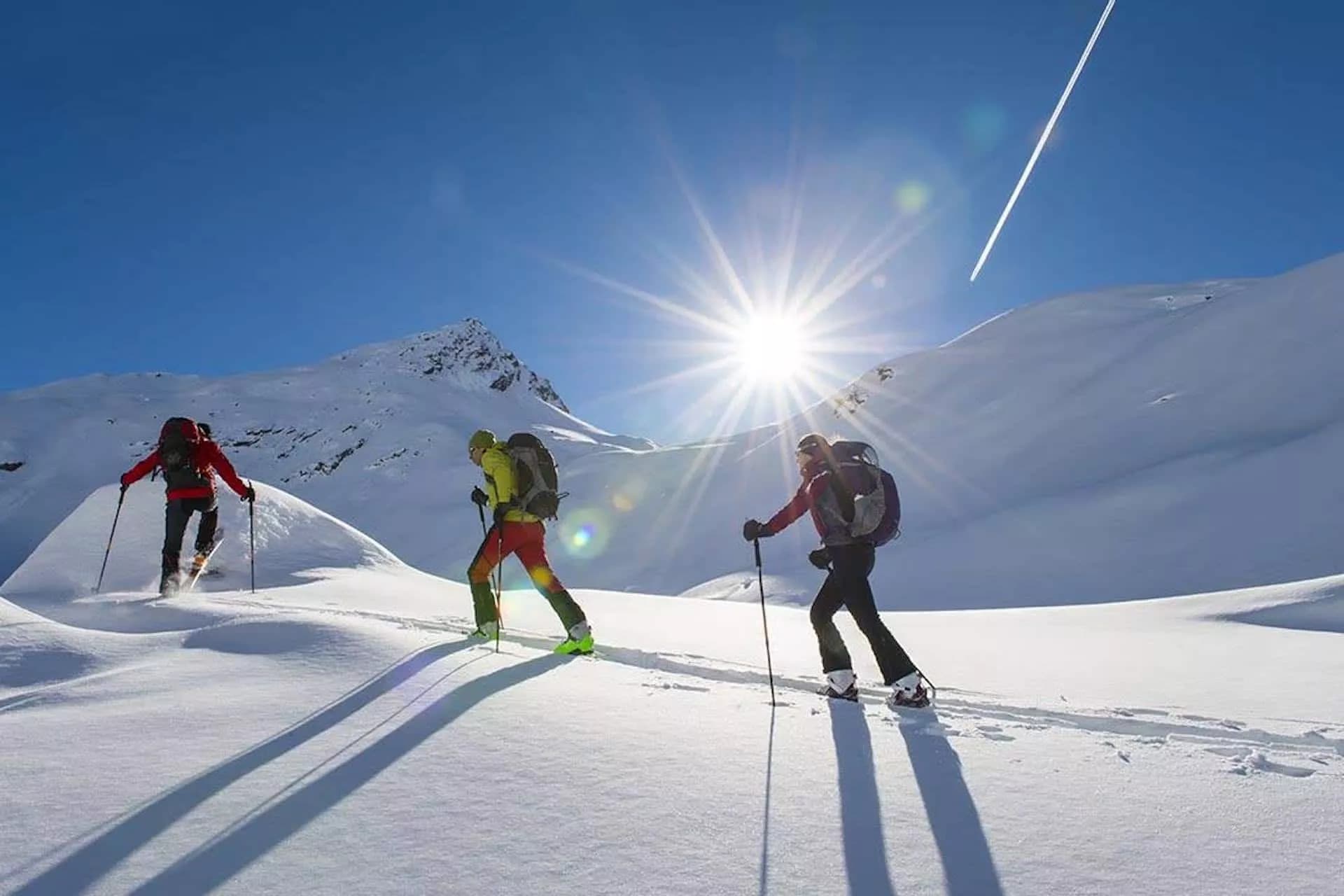 Ski touring in Triglav National Park with bright sun and snow-covered mountains.