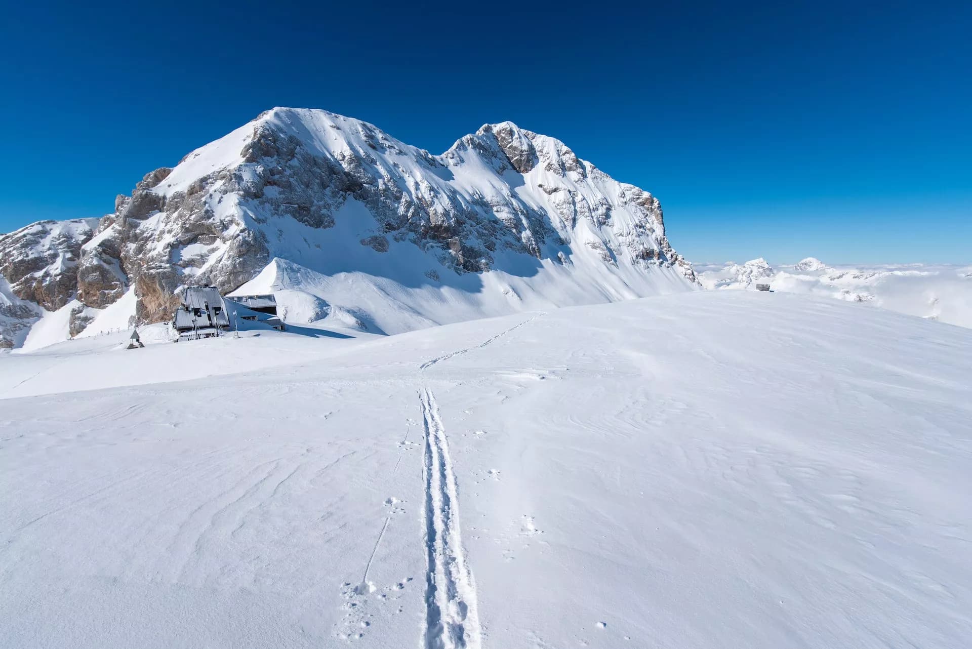 Ski tracks across snow leading toward Kredarica and Triglav mountains in winter.